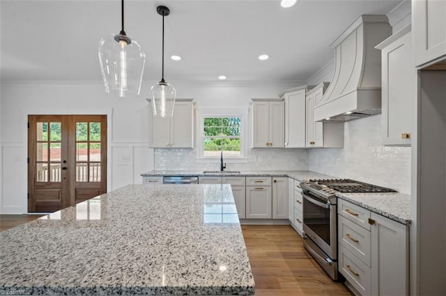 kitchen with appliances with stainless steel finishes, premium range hood, a healthy amount of sunlight, and french doors