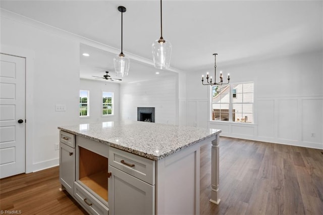 kitchen featuring ceiling fan with notable chandelier, a fireplace, dark hardwood / wood-style floors, hanging light fixtures, and a center island