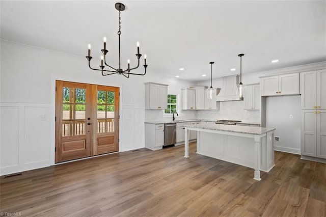 kitchen with wood-type flooring, premium range hood, dishwasher, and a center island