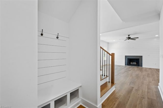 mudroom featuring light wood-type flooring, a fireplace, ceiling fan, and vaulted ceiling