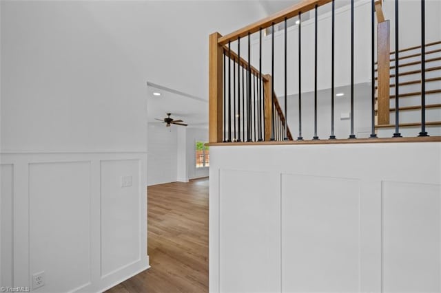 stairway with hardwood / wood-style floors and ceiling fan