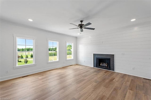 unfurnished living room with ornamental molding, light hardwood / wood-style flooring, ceiling fan, and a tile fireplace