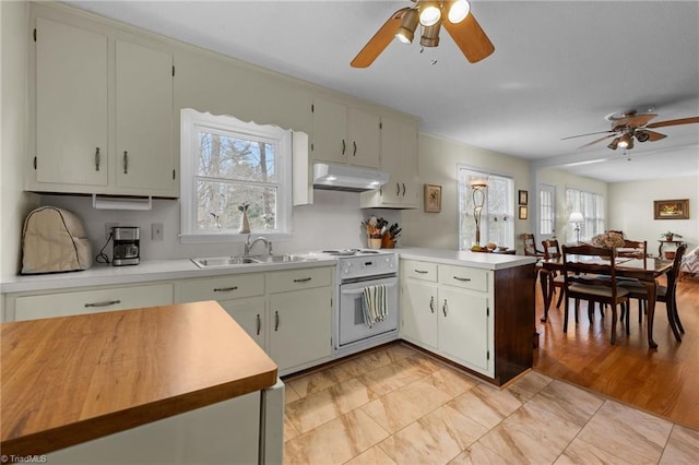kitchen with ceiling fan, a peninsula, under cabinet range hood, a sink, and white electric stove