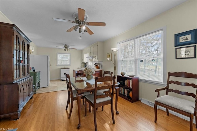dining area with light wood-type flooring, baseboards, a ceiling fan, and visible vents