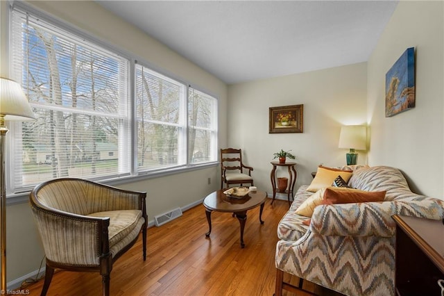 living area featuring visible vents, light wood-type flooring, and baseboards