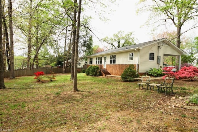 rear view of house featuring fence and a lawn