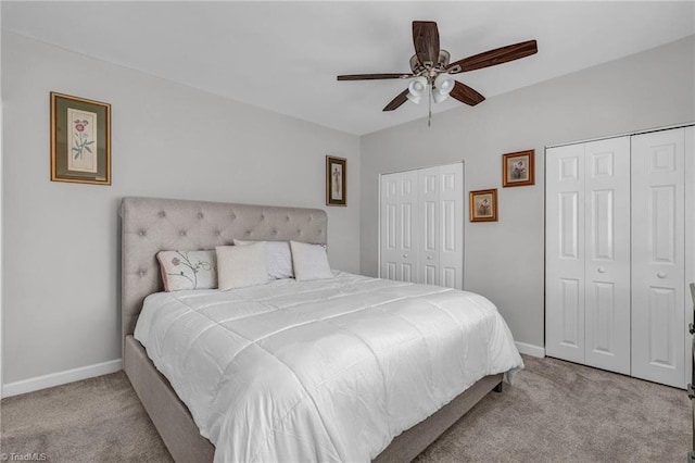 bedroom with ceiling fan, light colored carpet, and two closets