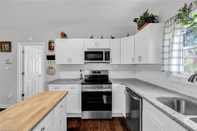 kitchen with white cabinets, sink, appliances with stainless steel finishes, light stone countertops, and dark hardwood / wood-style flooring