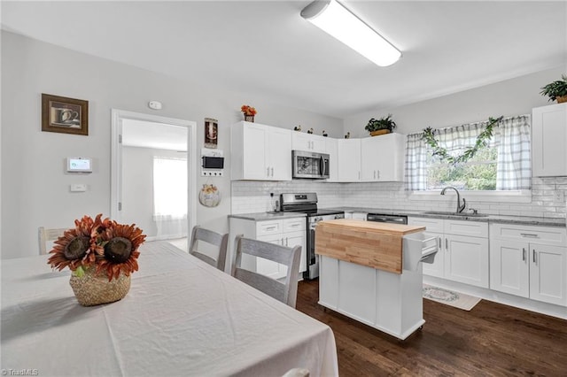 kitchen with white cabinetry, tasteful backsplash, dark hardwood / wood-style flooring, stainless steel appliances, and sink