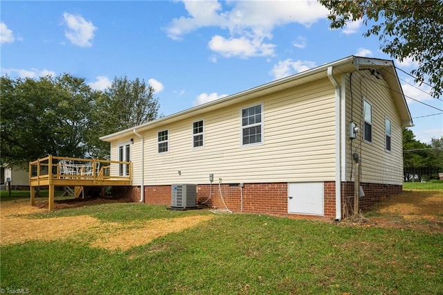 rear view of house featuring cooling unit, a deck, and a lawn