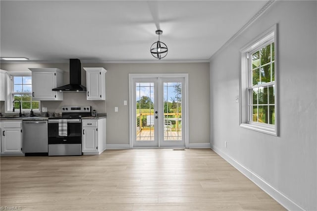 kitchen featuring white cabinetry, stainless steel appliances, wall chimney exhaust hood, and hanging light fixtures