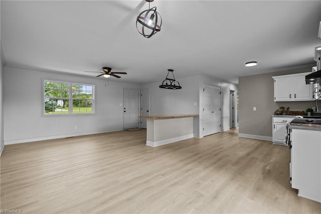 kitchen with light hardwood / wood-style flooring, crown molding, pendant lighting, white cabinetry, and ceiling fan