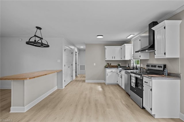 kitchen featuring wall chimney exhaust hood, pendant lighting, white cabinets, and stainless steel appliances