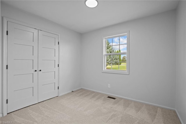 unfurnished bedroom featuring light colored carpet and a closet