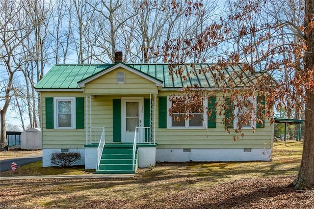 bungalow featuring a standing seam roof, metal roof, crawl space, and a chimney