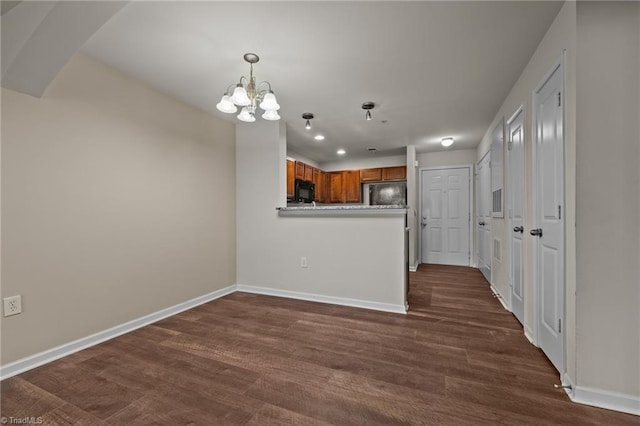 kitchen featuring fridge, a notable chandelier, dark hardwood / wood-style flooring, and kitchen peninsula