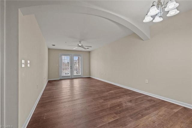 spare room featuring dark wood-type flooring, beam ceiling, ceiling fan with notable chandelier, and french doors