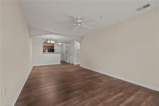 unfurnished living room featuring ceiling fan with notable chandelier and dark hardwood / wood-style floors