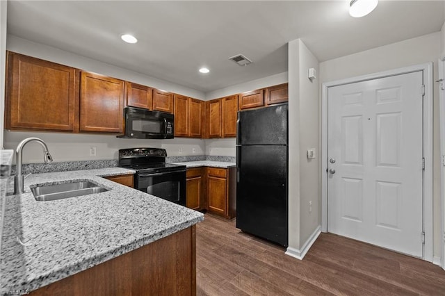 kitchen featuring light stone counters, dark wood-type flooring, sink, and black appliances