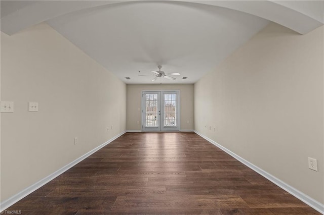 empty room featuring french doors, ceiling fan, and dark wood-type flooring