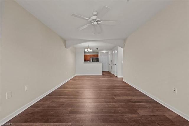 unfurnished living room with ceiling fan with notable chandelier and dark hardwood / wood-style flooring