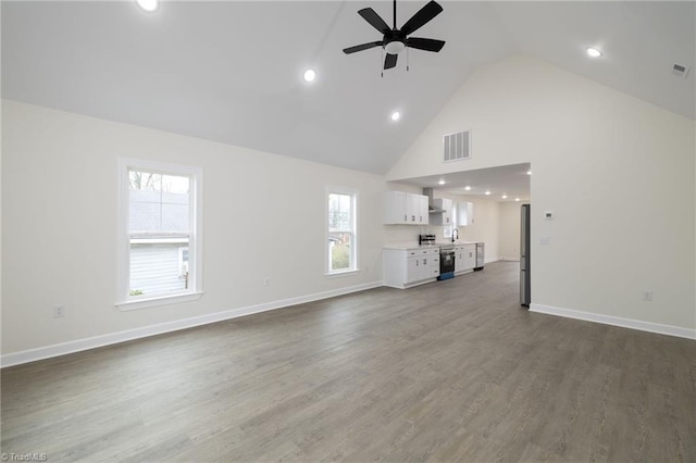 unfurnished living room with hardwood / wood-style flooring, high vaulted ceiling, plenty of natural light, and ceiling fan