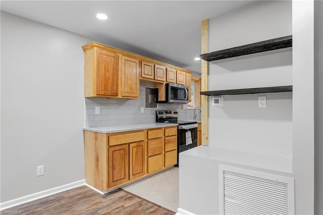 kitchen with backsplash, stainless steel appliances, and light hardwood / wood-style floors