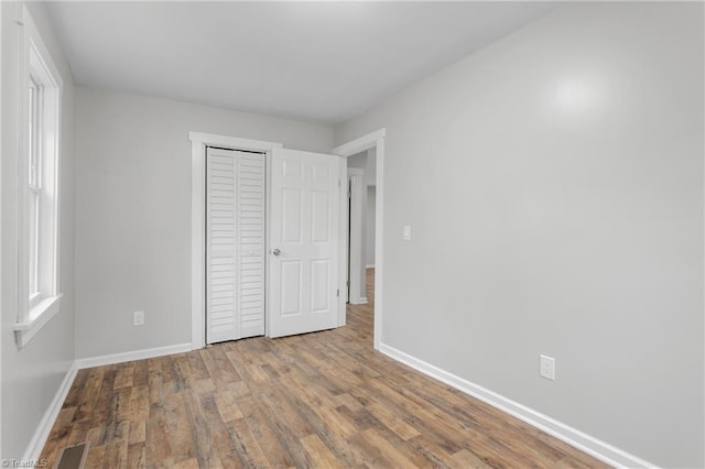 unfurnished bedroom featuring multiple windows, hardwood / wood-style flooring, and a closet