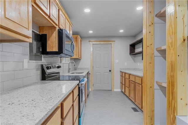 kitchen with sink, light brown cabinets, appliances with stainless steel finishes, light stone countertops, and decorative backsplash