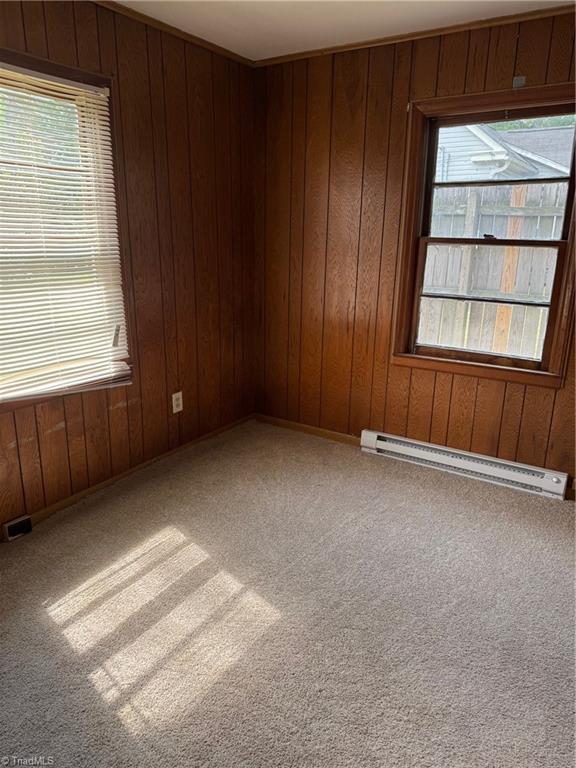 208-210 Long St, Thomasville, NC 27360 - spare room featuring a baseboard heating unit, plenty of natural light, carpet floors, and wooden walls