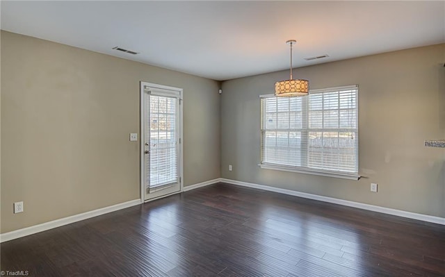 spare room featuring plenty of natural light and dark hardwood / wood-style floors