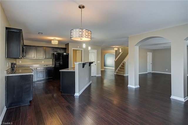 kitchen with black fridge, sink, a center island, dark hardwood / wood-style floors, and hanging light fixtures