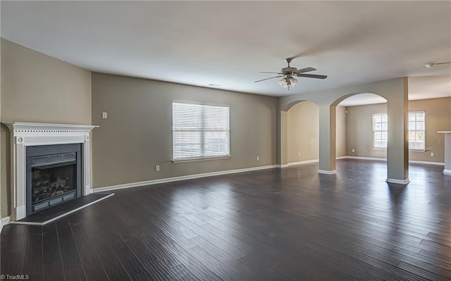 unfurnished living room with ceiling fan and dark wood-type flooring