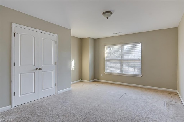 unfurnished bedroom featuring light carpet and a closet