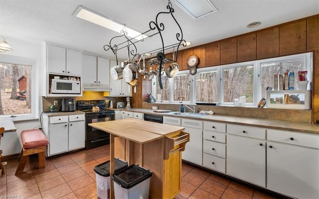 kitchen featuring light tile patterned floors, white cabinets, wood counters, under cabinet range hood, and black appliances