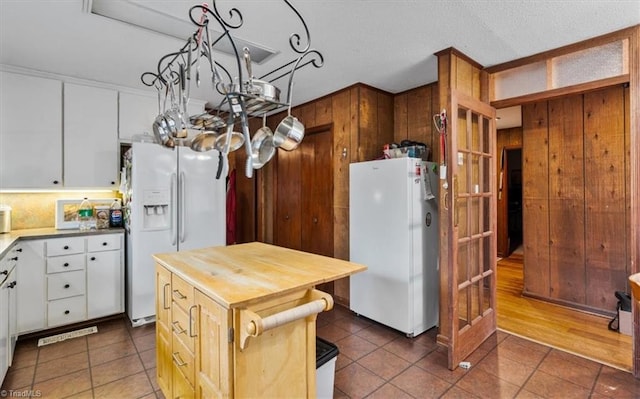 kitchen featuring wooden walls, white fridge with ice dispenser, wooden counters, and freestanding refrigerator