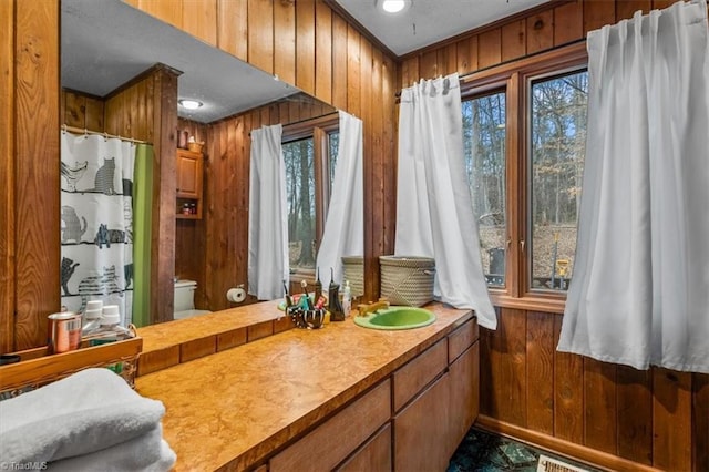 full bathroom featuring visible vents, toilet, a shower with curtain, vanity, and wood walls