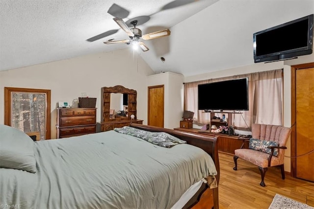 bedroom with lofted ceiling, ceiling fan, a textured ceiling, and wood finished floors