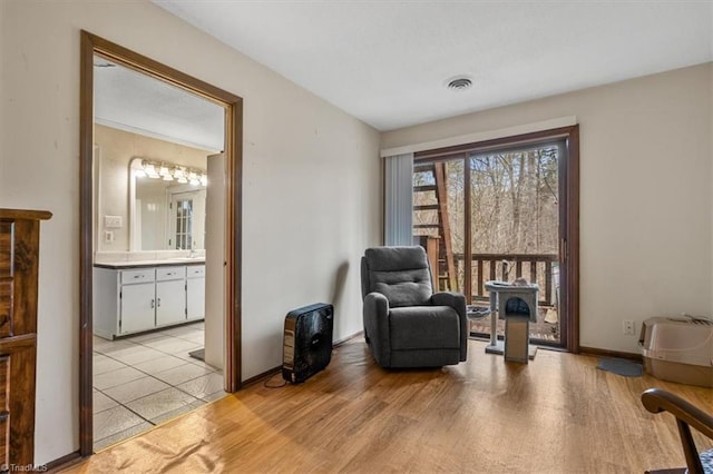 living area with baseboards, visible vents, and light wood-style floors