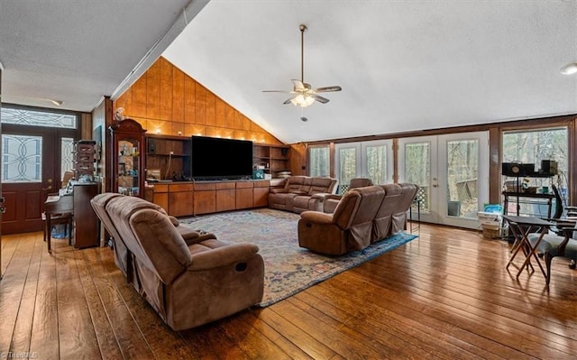 living room with wood-type flooring, plenty of natural light, and wooden walls