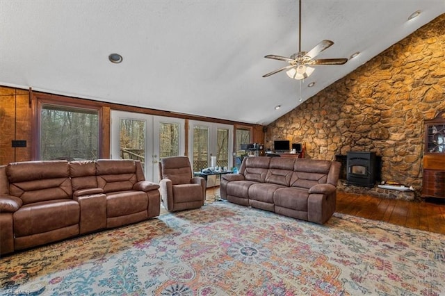 living room featuring lofted ceiling, ceiling fan, french doors, hardwood / wood-style floors, and a wood stove