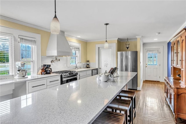 kitchen with stainless steel appliances, decorative light fixtures, a breakfast bar area, and white cabinets