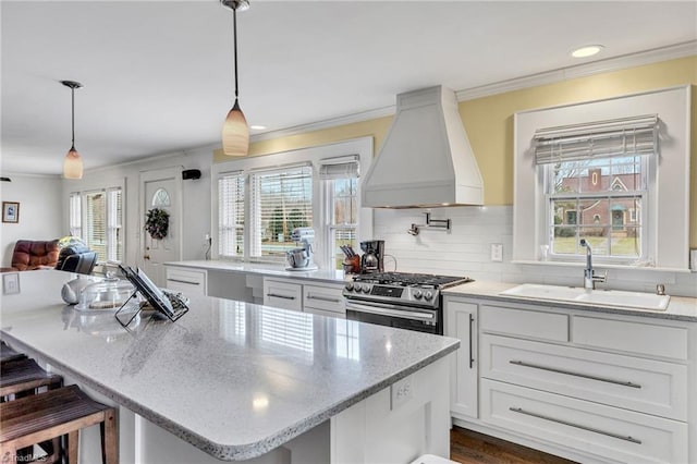 kitchen with premium range hood, a breakfast bar, decorative light fixtures, white cabinets, and gas stove