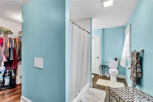 bathroom with hardwood / wood-style flooring, curtained shower, and toilet