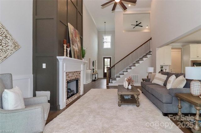 living area with crown molding, stairs, dark wood-style floors, ceiling fan, and visible vents