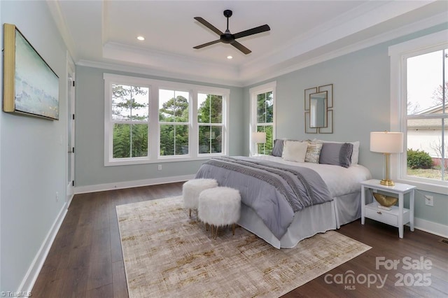 bedroom featuring a tray ceiling, crown molding, recessed lighting, dark wood-type flooring, and baseboards
