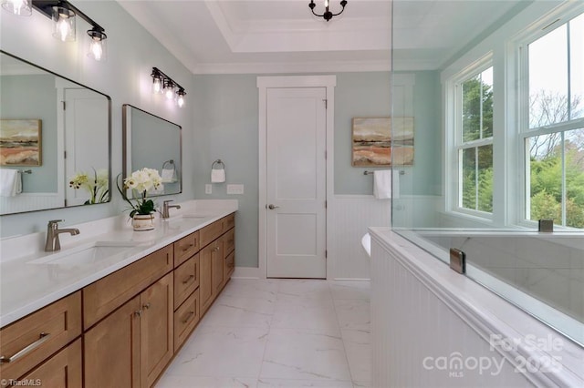 full bath with marble finish floor, a sink, double vanity, and wainscoting