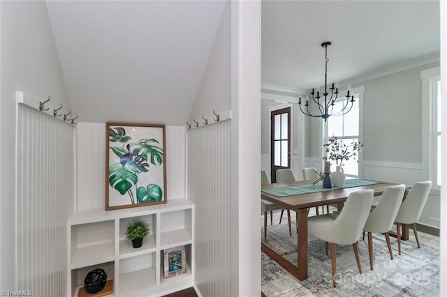 dining area with vaulted ceiling, wainscoting, crown molding, and a chandelier