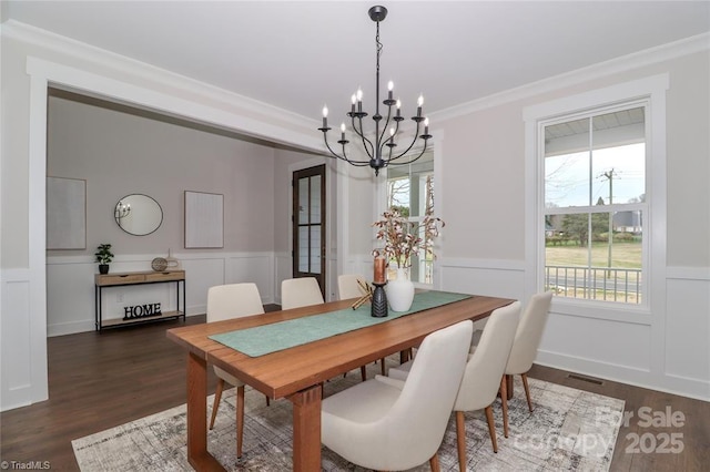 dining room featuring dark wood-style flooring, a wainscoted wall, visible vents, a chandelier, and crown molding