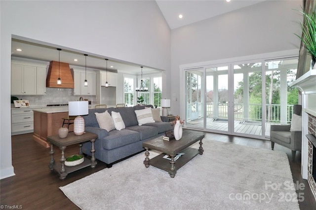 living area featuring a fireplace, high vaulted ceiling, recessed lighting, and dark wood finished floors